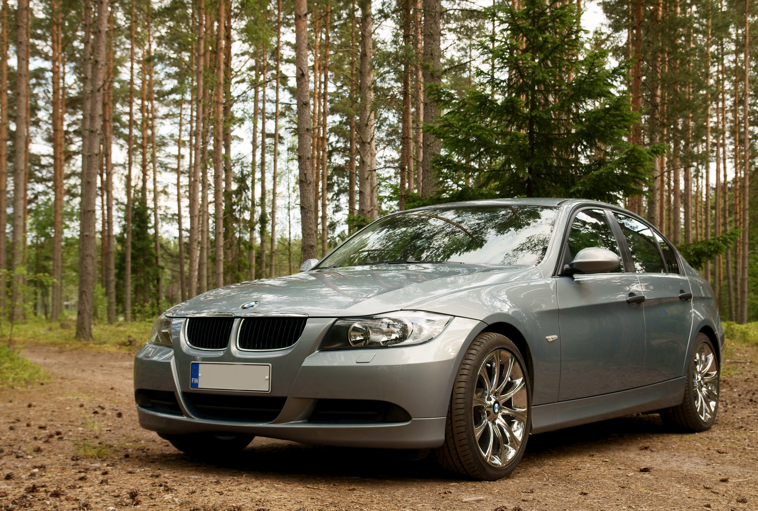 Серебристый седан BMW 3 серии E90 рядом с финским лесом