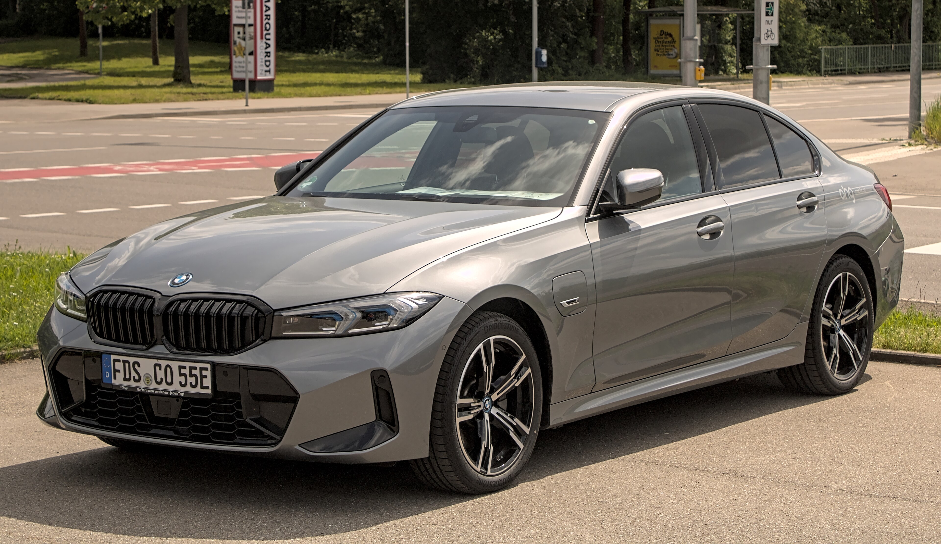 Серый седан BMW 320e поколения G20 в ракурсе три четверти спереди